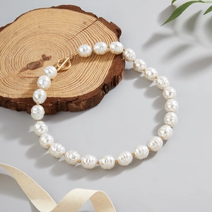 Baroque pearl necklace with gold OT toggle clasp on a natural wood slice background