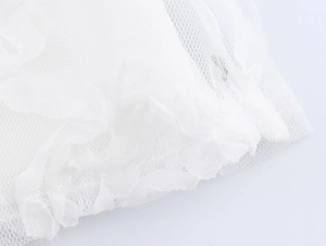 Detailed close-up showing white mesh fabric texture and layered tulle pleats of the dress