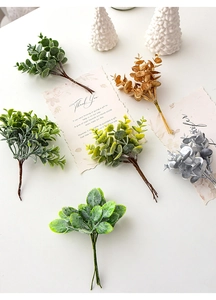 Flat lay of artificial pine branches in multiple colors on a clean white background