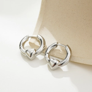 Detailed view of silver hoop earrings featuring polished 3D heart charms and glossy finish