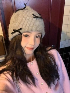 Close-up of gray knit beanie featuring black velvet bows and soft bunny hair texture