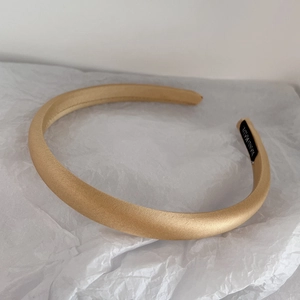 Close-up of golden satin padded headband with handmade label on soft textured paper