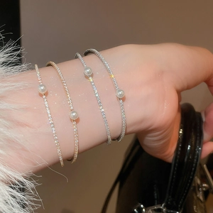 Detail of elegant gold and silver thin bangles featuring pearls worn on a wrist
