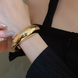 Close-up of minimalist chunky golden cuff bracelet with polished mirror finish