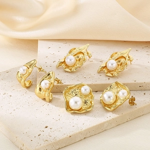 Détail de boucles d'oreilles en acier doré 18k avec texture de lave et perles blanches