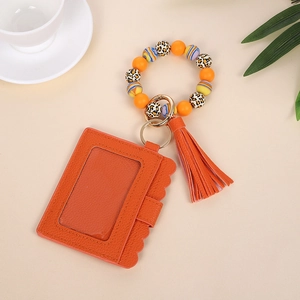 Macro detail of orange silicone beaded wristlet with leather card holder and tassel