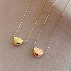 Minimalist heart pendant necklace in gold and rose gold titanium steel on textured fabric