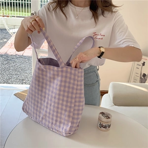 Bolso tote de lona a cuadros lavanda minimalista llevado al hombro en un interior suave