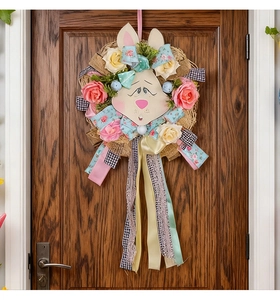 Detail of Easter wreath with cartoon bunny, pastel roses, and colorful festive ribbons on a door