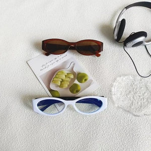 Detail view of retro cat-eye sunglasses with oval frames on a stylish white textured surface