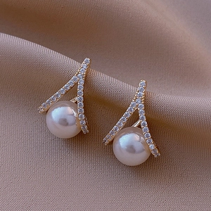 Detail of elegant champagne gold floral earrings with pearls and crystal inlay on silk