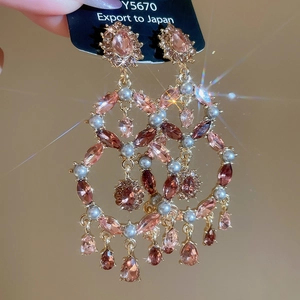 Detail of luxury pink crystal drop earrings with vintage pearls and sparkling gemstones