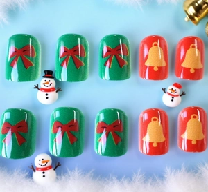 Detail of Christmas press-on nails with red bows, gold bells, and festive winter decor