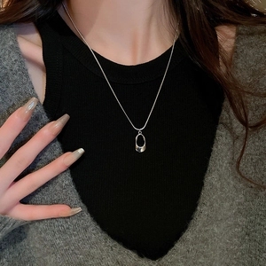 Detail of silver stainless steel oval geometric necklace worn on neck with casual outfit