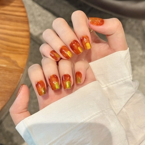 Amber tortoiseshell press-on nails with gold foil accents and a glossy finish