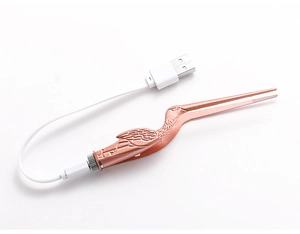 Macro view of rose gold flamingo earwax removal tool with white USB charging cable