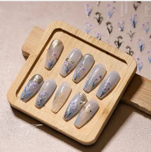 Macro shot of 5D long trapezoid press-on nails with purple floral art and gold foil