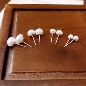 Macro shot of four pairs of freshwater pearl earrings in varying sizes on a walnut display box