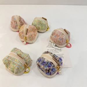 Colorful plaid tweed earbud pouches with pearl pendants and gold zippers in a neat layout