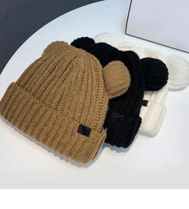 Détail montrant trois bonnets à oreilles d'ours en marron, noir et beige tricoté