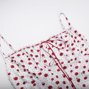 Detalle de estampado de rosas rojas con lunares negros, encaje blanco y lazo rojo