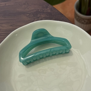 Detailed view of translucent green butterfly hair claw clip on a ceramic plate