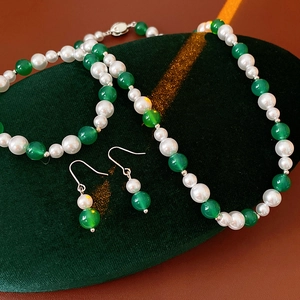 Dettaglio di collana e orecchini vintage con perle bianche e gemme verdi