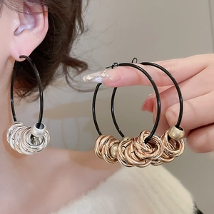 Detail of twisted round earrings in black, gold and silver finishes on model