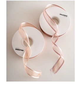 Detail of elegant semi-transparent organza ribbon rolls in soft champagne gold and pink