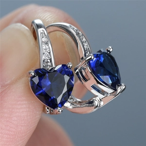 Macro shot of heart-shaped blue sapphire drop earrings with small cubic zirconia details