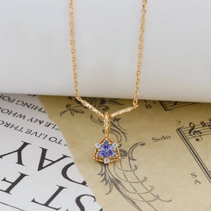 Dettaglio di una collana placcata in oro 14K con pendente a triangolo in gemma viola