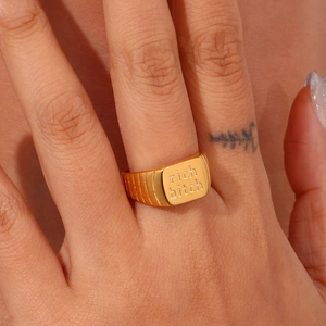 Goldener Siegelring mit RICH BITCH Gravur am Finger, minimalistischer Modeschmuck