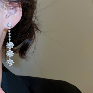 Detail of silver long floral diamond earrings worn by model with elegant sparkling finish
