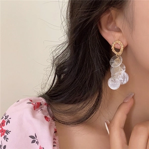 Elegant gold textured hoop earrings with dangling translucent shell discs on model