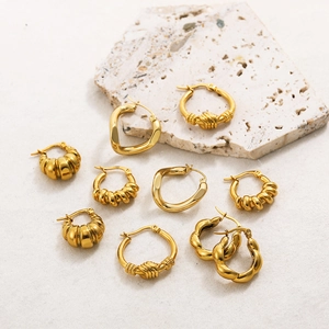 Chic hollow gold stainless steel hoop earrings with various textures on stone background
