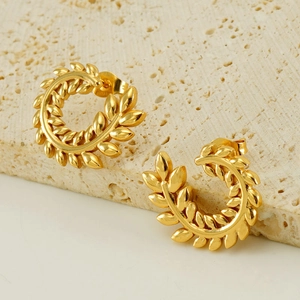 Elegant gold wheat ear hoop earrings displayed on a natural travertine stone stand