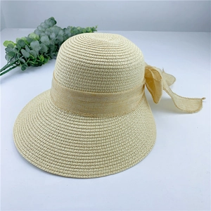 Détail d'un chapeau de plage en paille beige avec nœud élégant et texture tressée fine