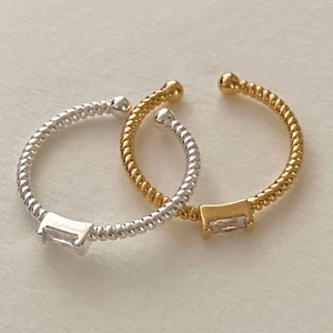 Dettaglio anello a corda intrecciata con zircone rettangolare in finitura oro e argento