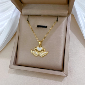 Close-up of golden swan heart pendant with shell inlay and crystals in a jewelry box