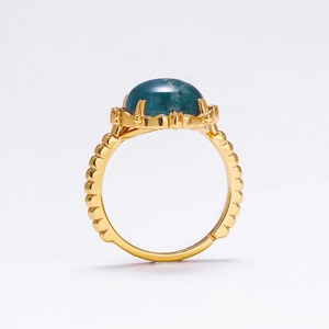 Macro side view of a gold S925 silver ring featuring a green moss stone and wavy band