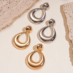 Modern hollow teardrop earrings in gold and silver finish on a natural stone base