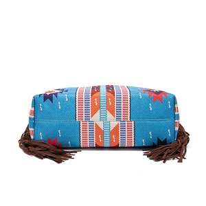 Detail view of Bohemian woven bag featuring blue geometric patterns and brown leather tassels