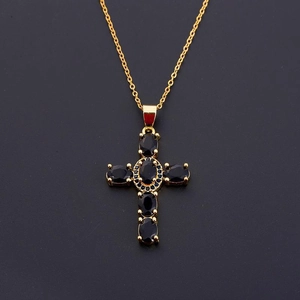 Close-up of gold cross pendant featuring micro-set black oval and small round zircons