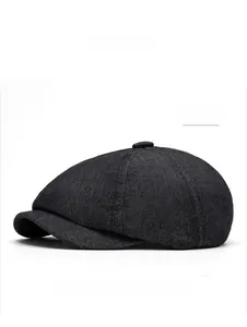 Detailed close-up of a black denim newsboy cap featuring classic eight-panel texture