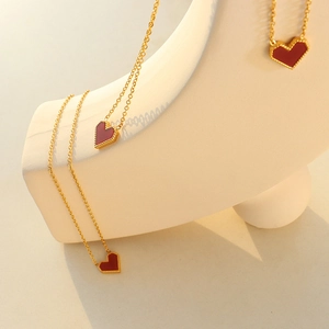 Close-up of golden triple snake chain necklaces with elegant red heart-shaped pendants