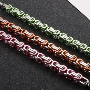 Macro shot of interlocking punk style stainless steel chain bracelets in green orange and pink