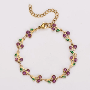 Detailed shot of golden cherry bracelet with purple gems and green enamel leaf accents