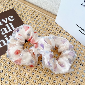 Close-up of floral organza scrunchies with heart patterns on a woven background