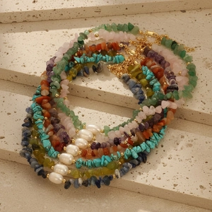 Bohemian style necklace with natural gemstones, pearls and gold beads on stone display