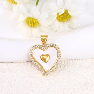 Macro shot of gold heart pendant with white shell inlay and micro-paved crystals detail